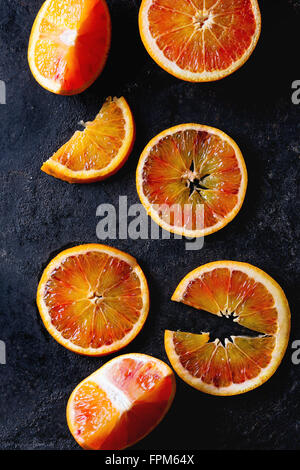 Sliced Sicilian Blood oranges fruits over black metal background. Top view Stock Photo