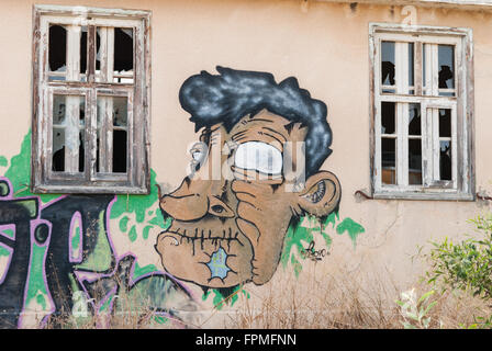 Fragment of the wall old abandoned house with broken windows and graffiti. Stock Photo