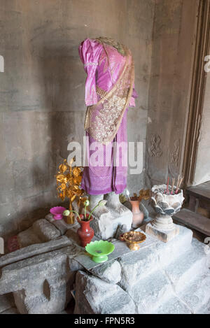 Angkor Wat, Cambodia - January 29 2016: headless statue to Buddhas wife in a shrine with incense and offerings in the 12th Centu Stock Photo