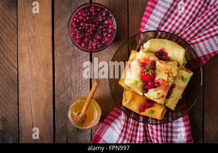 Golden pancakes with cranberry jam and honey in a rustic style. Top view Stock Photo