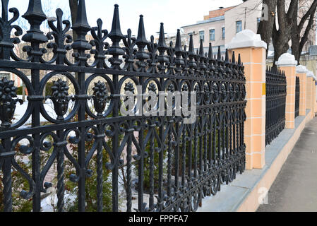 Black painted iron fence mounted at  small wall of brickstones Stock Photo
