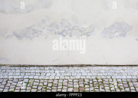 Weathered stucco wall and cobblestones of a church in Prague Stock Photo
