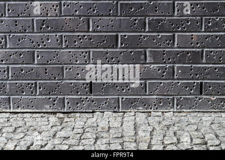Modern dark brick wall with grey pavement ground Stock Photo
