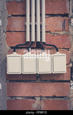 group of four light switches on brick wall Stock Photo
