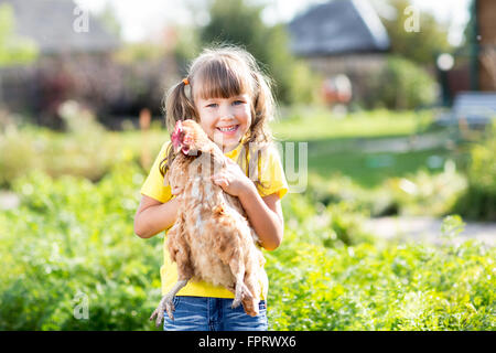 Child little girl with hen outdoor Stock Photo