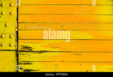 Brightly colored yellow orange wood background with grunge cracked boards and a metal plate with rivets in a full frame texture Stock Photo