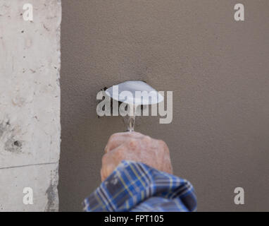 Close-up of hand using trowel to finish wet concrete wall at construction site Stock Photo