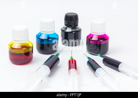 Syringes to make a home made refill of an inkjet printer, next to four bottles with yellow, magenta, cyan and black ink colors Stock Photo