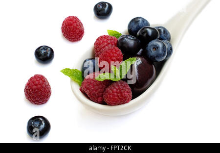 Ceramic spoon full of raspberries,cherries and blueberries isolated on white. Stock Photo