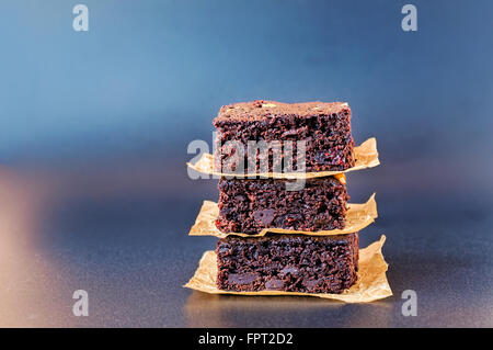 Three stacked chocolate chip brownies on dark blue background. Stock Photo