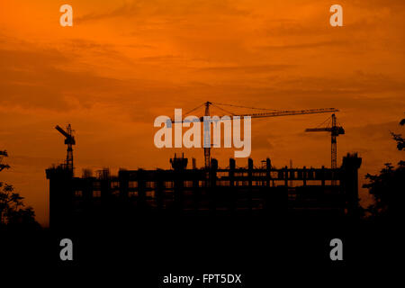 Silhouette of tower crane on a building construction site at sunset Stock Photo