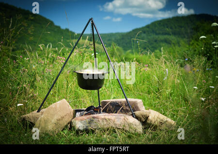 Tourist pot hanging over the fire on a tripod Stock Photo