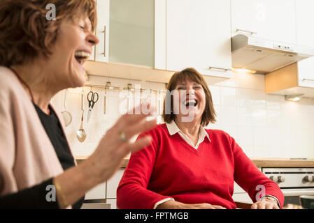 Two senior women talking and laughing in kitchen, Munich, Bavaria, Germany Stock Photo