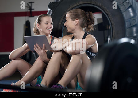 Two women relaxing and using digital tablet after exercise, Bavaria, Germany Stock Photo