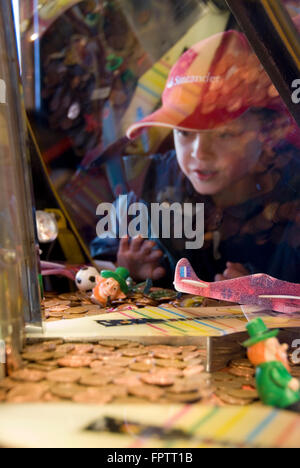 Cleethorpes, Lincolnshire, UK - 18 April 2014: Boy gambling at penny drop machines on 18 April at Cleethorpes, UK Stock Photo