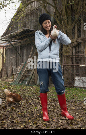 Farmer woman with white chicken bird in farm, Bavaria, Germany Stock Photo