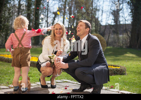 Son throwing flower petals on bride and groom, Munich, Bavaria, Germany Stock Photo