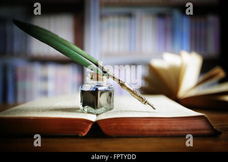 Quill pen on an old book in a library Stock Photo