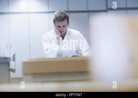 Young male scientist reading book in the lecture room, Freiburg Im Breisgau, Baden-Württemberg, Germany Stock Photo