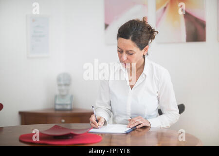 Female doctor writing prescription in hospital, Freiburg Im Breisgau, Baden-Württemberg, Germany Stock Photo