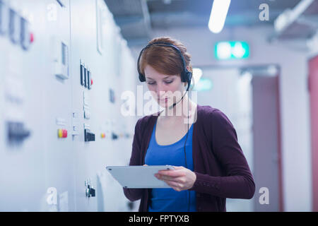 Young female engineer updating control panel by digital tablet in industry, Freiburg Im Breisgau, Baden-Württemberg, Germany Stock Photo