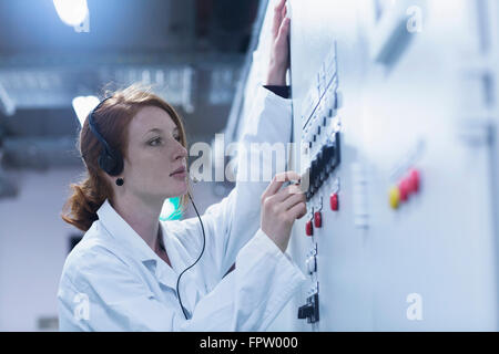 Young female engineer wearing headset and controlling a switch gear in control room, Baden-Württemberg, Germany Stock Photo