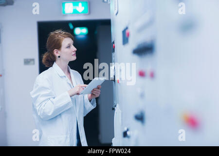 Young female engineer updating control panel by digital tablet in an industry, Freiburg Im Breisgau, Baden-Württemberg, Germany Stock Photo