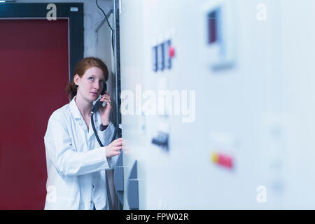 Young female engineer talking on landline phone in control room, Freiburg Im Breisgau, Baden-Württemberg, Germany Stock Photo