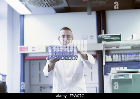 Young scientist arranging test tubes in test tube rack at pharmacy laboratory, Freiburg Im Breisgau, Baden-Württemberg, Germany Stock Photo