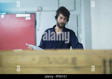 Young engineer wearing headset and checking cargo container in an industry, Freiburg Im Breisgau, Baden-Württemberg, Germany Stock Photo