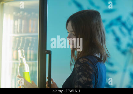 Young woman taking a soda bottle out of refrigerator, Freiburg Im Breisgau, Baden-Württemberg, Germany Stock Photo