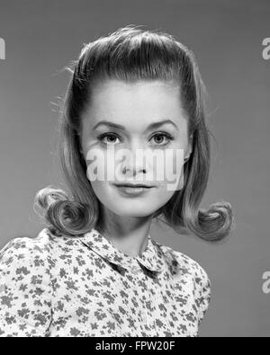 1960s PORTRAIT OF SERIOUS YOUNG WOMAN WITH FLIP HAIR STYLE AND WEARING PRINT BLOUSE LOOKING AT CAMERA Stock Photo