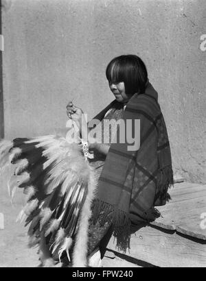 1930s NATIVE AMERICAN INDIAN WOMAN SEWING FEATHERED HEADDRESS WAR BONNET SAN ILDEFONSO PUEBLO NEW MEXICO USA Stock Photo