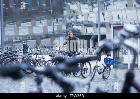 Young student standing outside parking lot with bicycle and talking on mobile phone, Baden-Württemberg, Germany Stock Photo