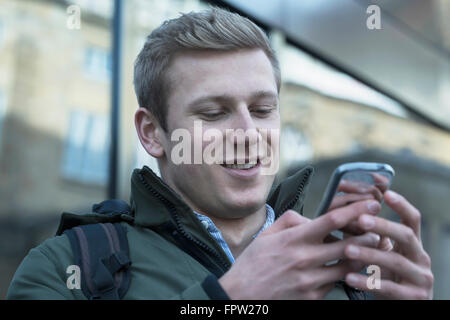 College student reading message on mobile phone, Freiburg im Breisgau, Baden-Württemberg, Germany Stock Photo
