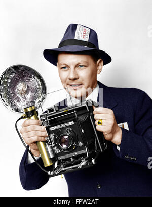 1930s 1940s 1950s MAN PRESS PHOTOGRAPHER HOLDING SPEED GRAPHIC CAMERA WITH FLASH BULB ILLUMINATION Stock Photo