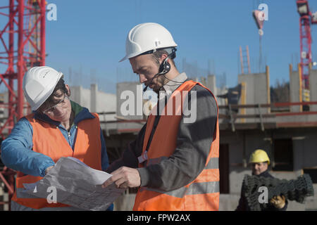 Two engineers looking at a blueprint at construction site, Freiburg Im Breisgau, Baden-Württemberg, Germany Stock Photo