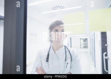Young female doctor looking at notes on hospital door, Freiburg im Breisgau, Baden-Württemberg, Germany Stock Photo