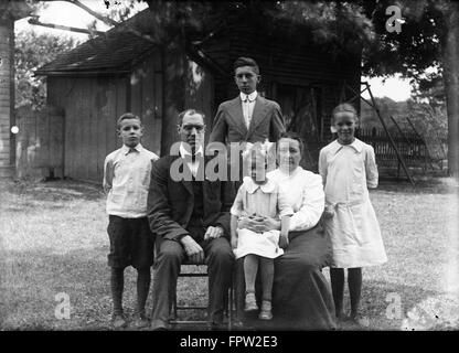 1900s 1918 FAMILY PORTRAIT MOTHER FATHER CHILDREN TWO SONS TWO DAUGHTERS POSING OUTSIDE IN BACKYARD LOOKING AT CAMERA Stock Photo