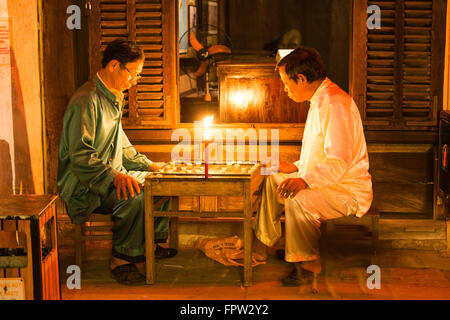 Men playing at the light of a candle a board game, Old Town of Hoi An, Vietnam Stock Photo