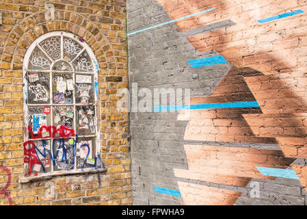 Classic victorian wooden window on a colored brick wall covered in scribbles and stickers Stock Photo