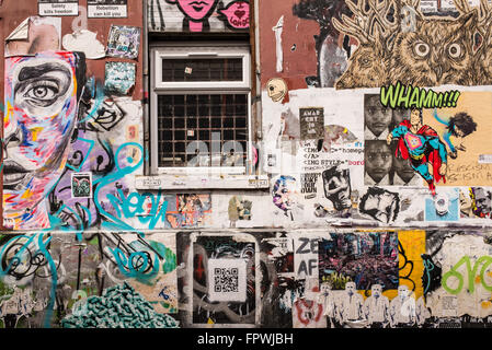 Wall covered in graffiti and wallpaper murals in the trendy area near Brick lane, Shoreditch, East London. Stock Photo