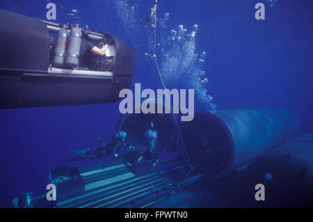 SEAL Delivery Vehicle (SDV) hovers in mid-water on tether to the Dry Deck Shelter (DDS) as the DDS crew stands by below to give Stock Photo