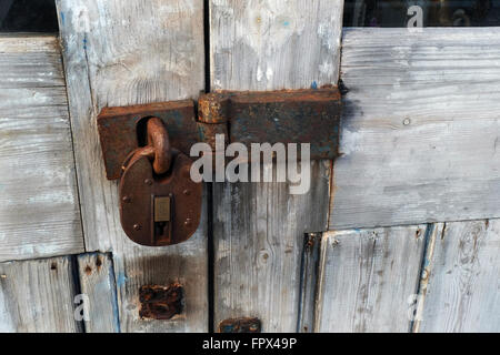 Rusting padlock and hasp on old wooden door. Stock Photo
