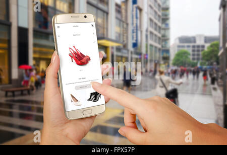 Online shopping with smart phone. Isolated phone in woman hand. Buying women shoes on online store. Stock Photo