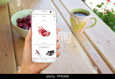 Online shopping with smart phone. Isolated phone in woman hand. Buying women shoes on online store. Stock Photo