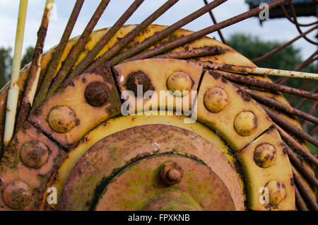 Rusting yellow farm machinery sitting in a paddock Stock Photo