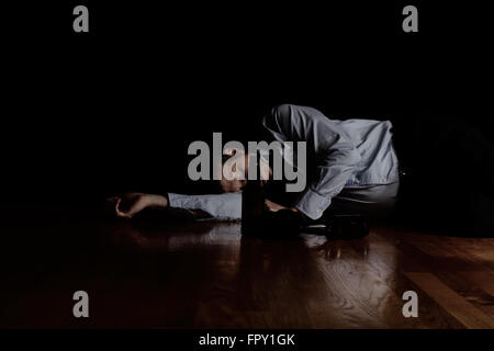 Depressed mature man sleeping on floor after getting drunk. Selective focus on beer bottles with man in background. Depression c Stock Photo