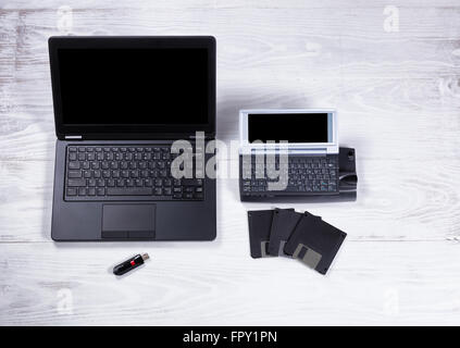 Overhead view of modern and an obsolete computer on white desktop with portable data devices. Stock Photo