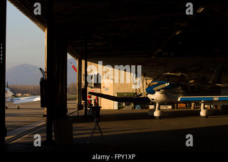 Small airport hangar scene with aircraft in late afternoon light Stock Photo